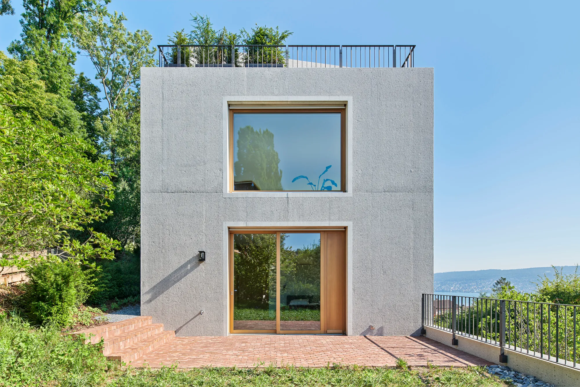 Harry Gugger Studio Folds a Concrete House into a Steep Wooded Hillside above Lake Zurich