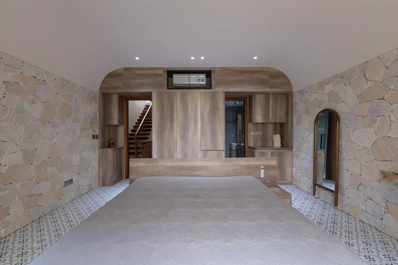 Interior space with irregular stone walls flanking a central timber alcove containing staircase and elevator