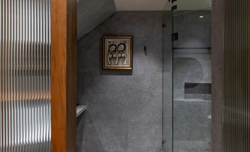Bathroom corner with fluted glass partition and recessed shower niche in grey terrazzo walls
