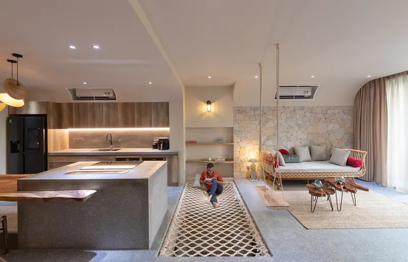 Open living area with kitchen island, irregular stone accent wall and child sitting on patterned rug