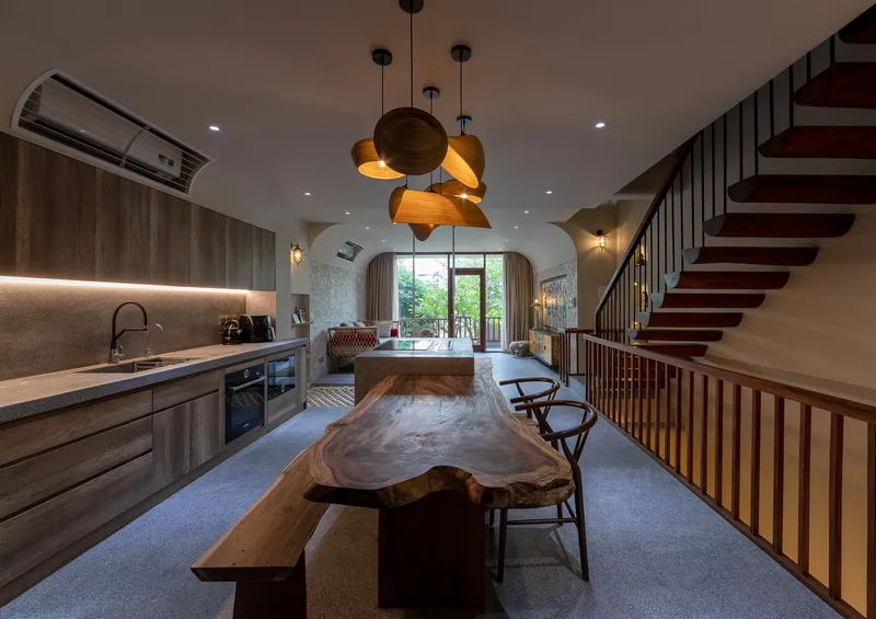 Dining area with live-edge timber table, cluster of wooden pendant lights, and view to greenery