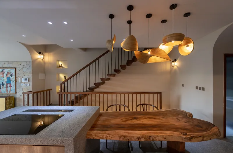 Sculptural cluster of laminated wood pendant lights suspended above the live-edge dining table and terrazzo counter