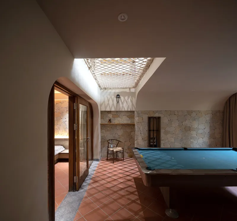 Interior corridor with terracotta tile floor and rope net skylight filtering daylight from above