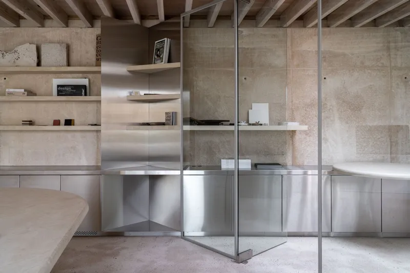 Interior shelving with plywood surfaces and stainless steel base cabinets reflected in glass partition