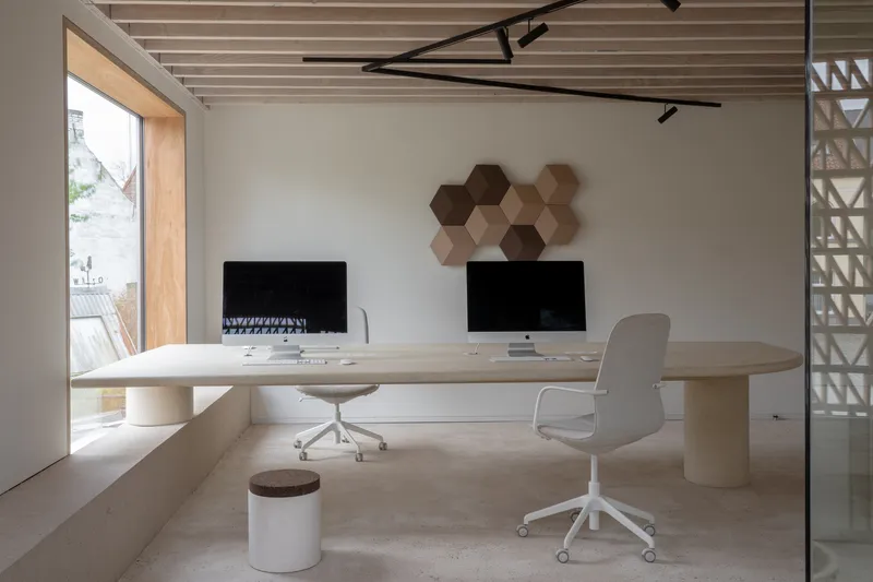 Office with light wood desk, exposed timber ceiling joists and hexagonal wall panels