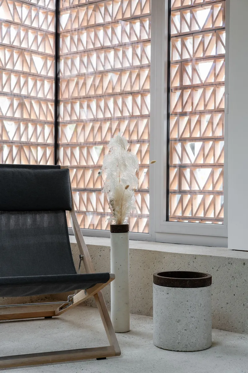 Timber lattice screen with triangular pattern filtering daylight into the terrazzo-floored interior