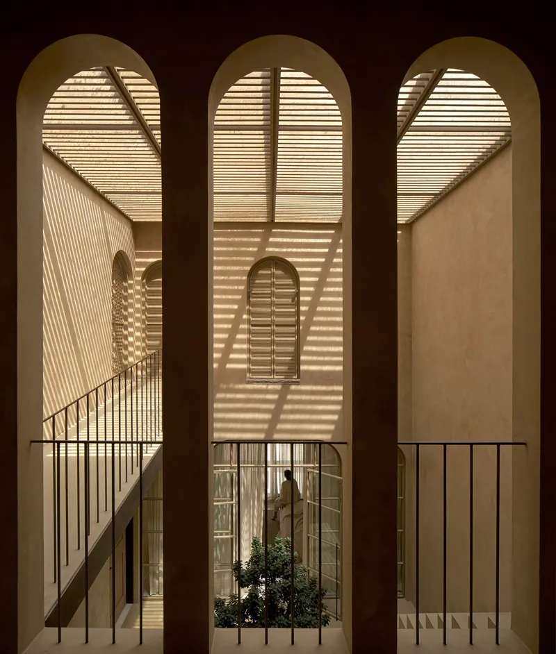 Triple arched openings framing the stairwell and courtyard with slatted light patterns at night