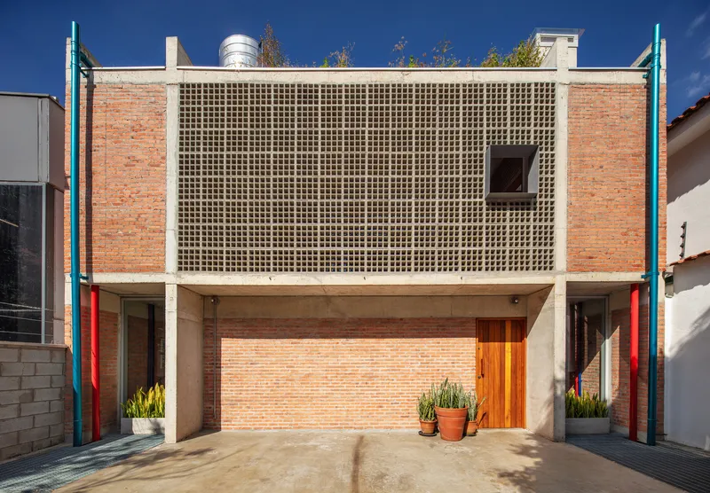 Front elevation showing the latticed upper facade flanked by exposed brick walls and blue steel columns