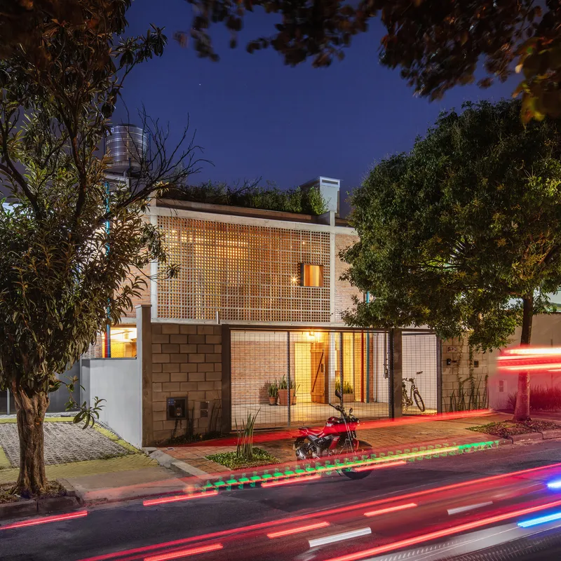 Street facade with concrete block screen and glass ground floor at twilight with traffic light trails