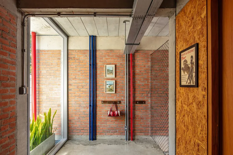 Interior hallway with exposed brick walls, concrete ceiling, blue and red painted steel columns and artwork