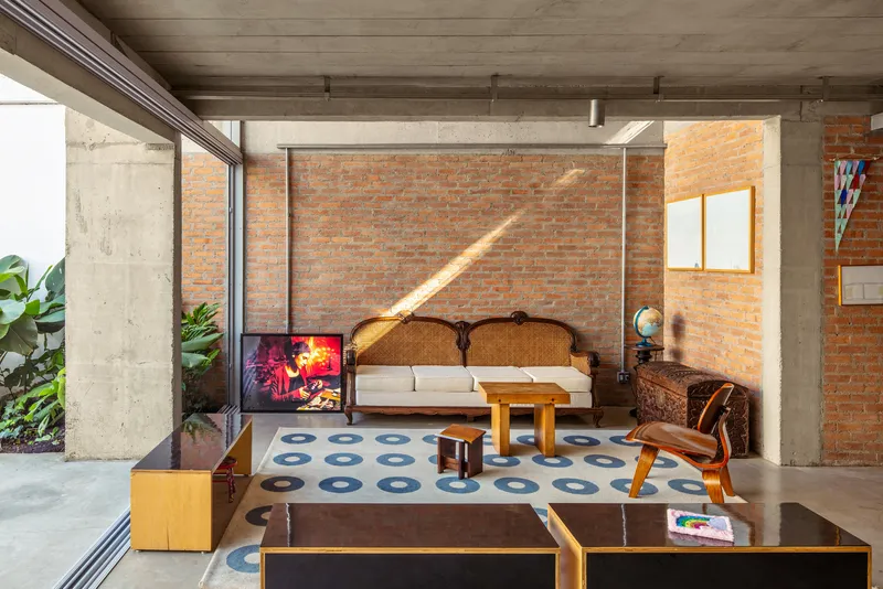 Living area with exposed brick walls and concrete ceiling bathed in afternoon sunlight from courtyard