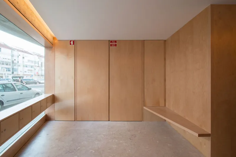 Plywood-paneled interior with built-in bench seating and storage cabinets below a street-level window