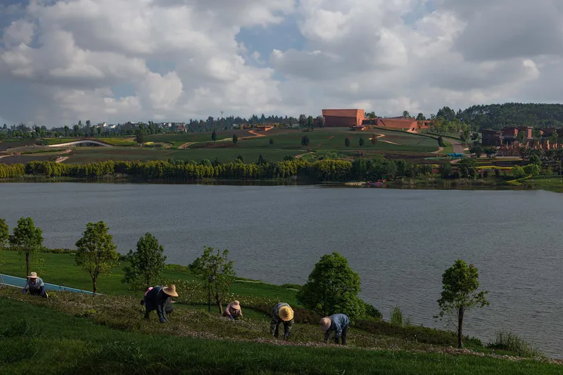 Distant view across the water of the compound on planted terraces under afternoon clouds