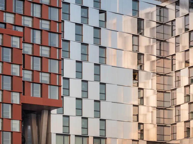 Corner junction of two facades showing terracotta and white panel grids in warm afternoon light