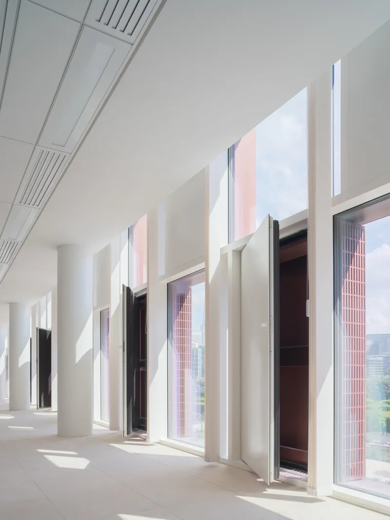 White corridor with deep-set windows and column coffers casting afternoon shadows across the floor