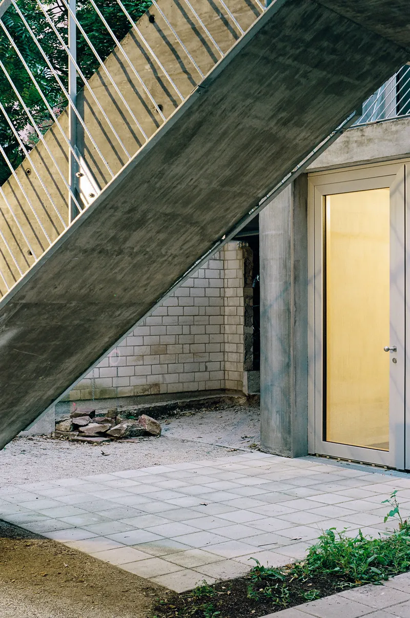 Exterior entry niche with paver courtyard beneath a sloping concrete roof and exposed brick wall