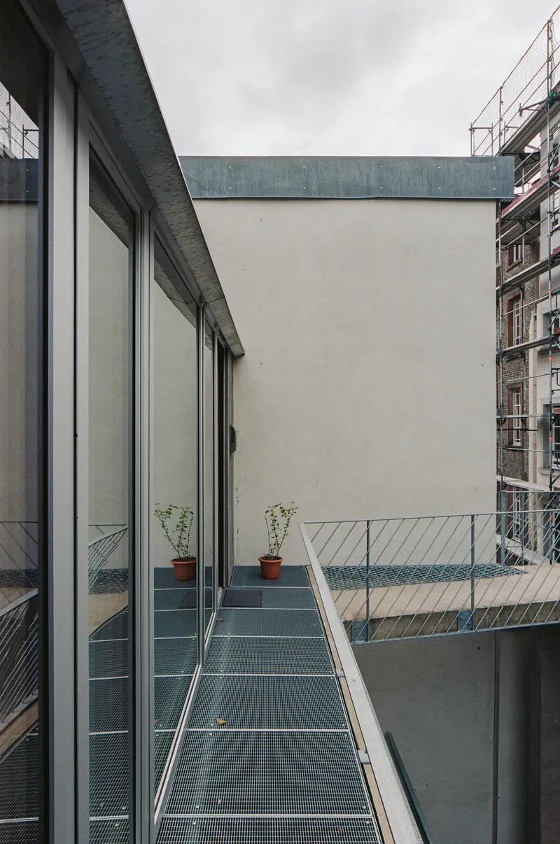 Metal grate walkway with potted plants and white railing under an overcast sky