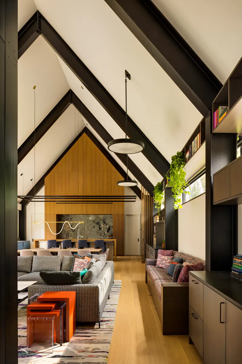 Double height living space with exposed black rafters and pendant lights above seating areas