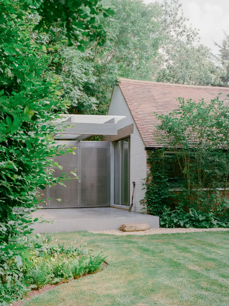Garden view of the white brick entry wing with cantilevered canopy and pitched tile roof beyond