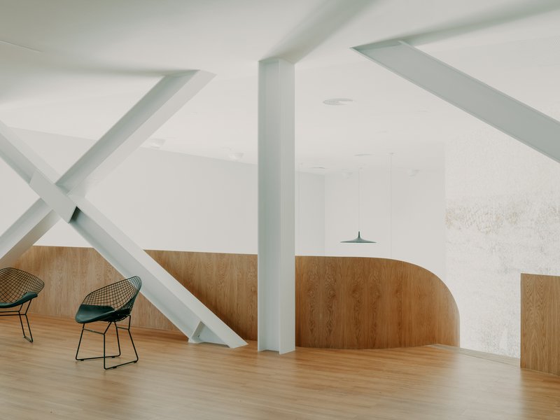 Upper level with curved plywood wall and exposed diagonal white steel bracing visible from below