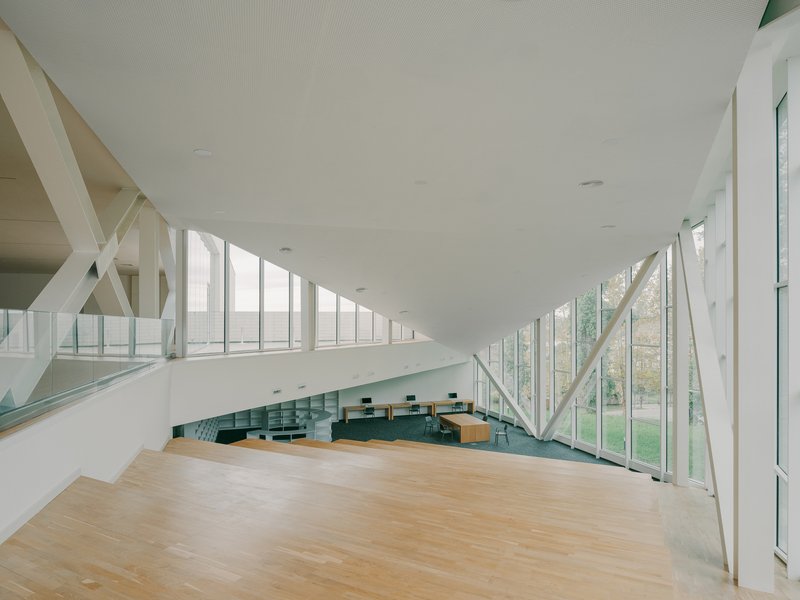 Mezzanine overlooking lower level with angled white beams and continuous glazed walls on both sides