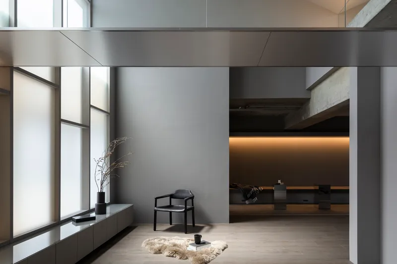 Corner reading nook with tall windows and view through to ambient-lit gallery beyond