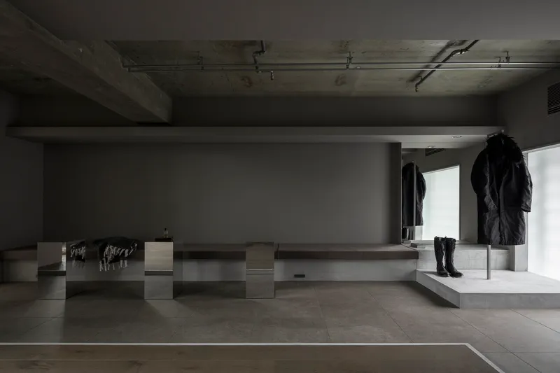 Retail display pedestals with garments beneath exposed concrete ceiling and recessed lighting