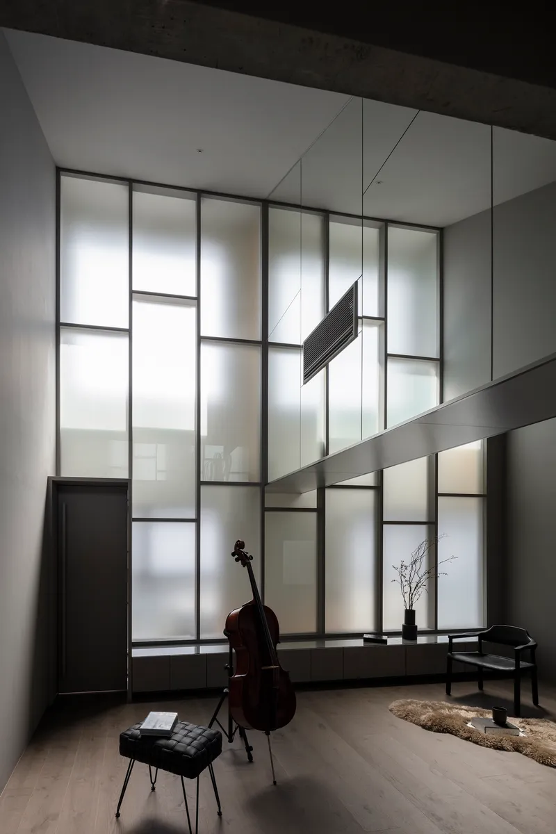 Translucent glass wall with suspended tubular light fixture and horizontal metal beam crossing the frame