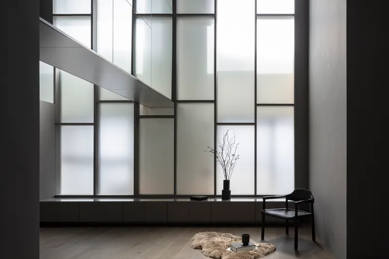 Gridded translucent glass wall with backlit panels above a continuous low platform along the floor