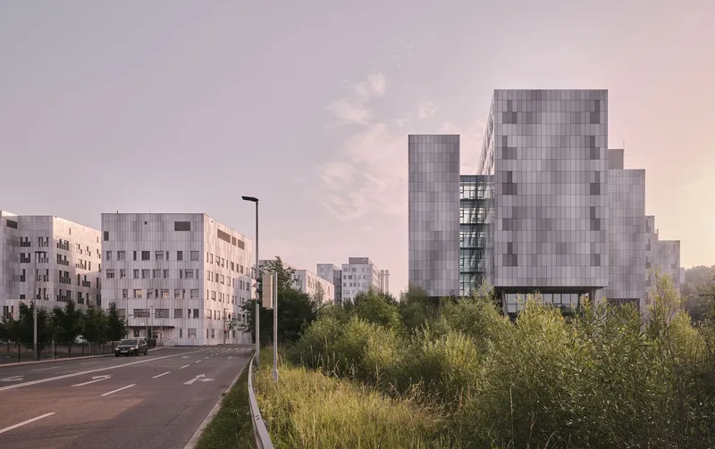 Cluster of panelized residential blocks adjacent to a roadway under a pink dusk sky