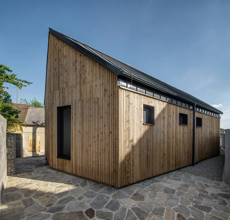 Long elevation of vertical timber cladding with square window openings and clerestory glazing