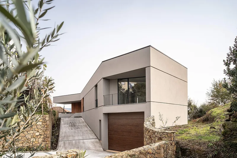 Angular massing defining a modern hillside residence with integrated garage access.