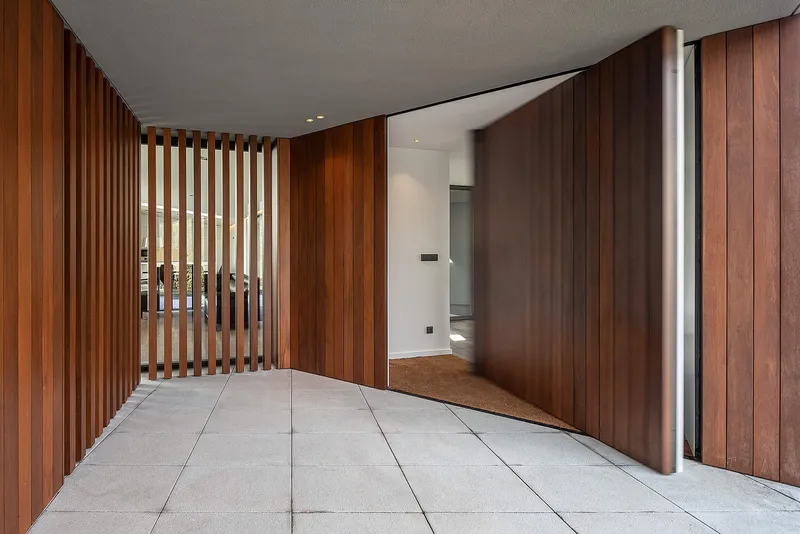 Warm wooden screens soften the transition between exterior and interior entry spaces.