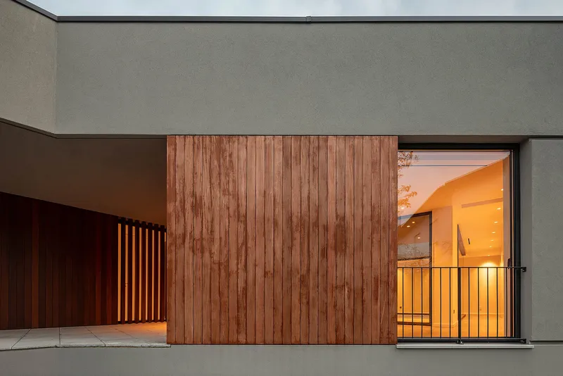 Textural contrast of concrete and timber with soft interior lighting spilling outward.