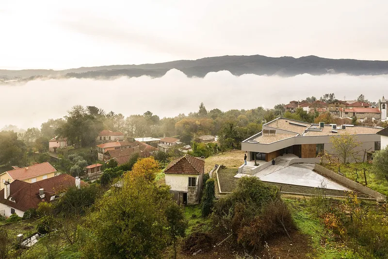 House positioned within a lush landscape, overlooking a misty valley context.