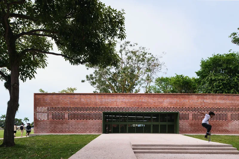 Front elevation showing patterned brickwork screen above glazed entrance with pedestrian crossing lawn