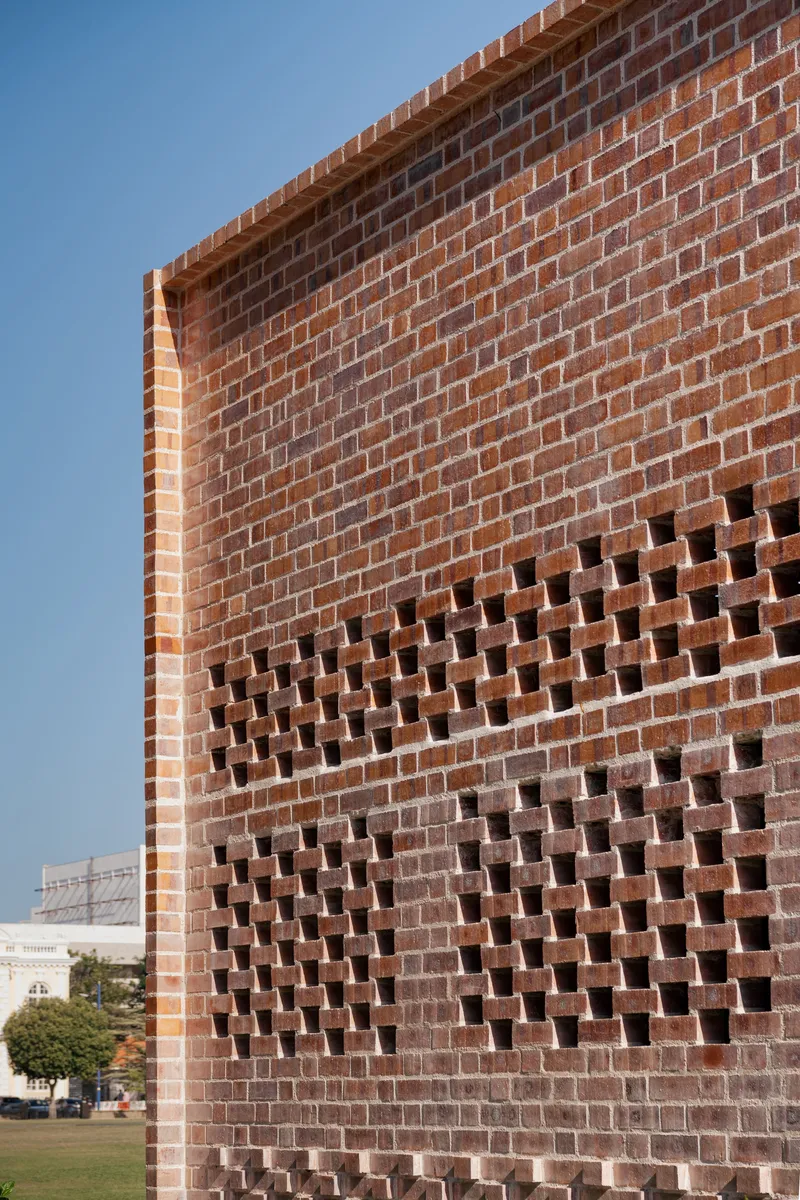 Corner detail of brick wall with protruding units forming ventilation pattern against clear sky