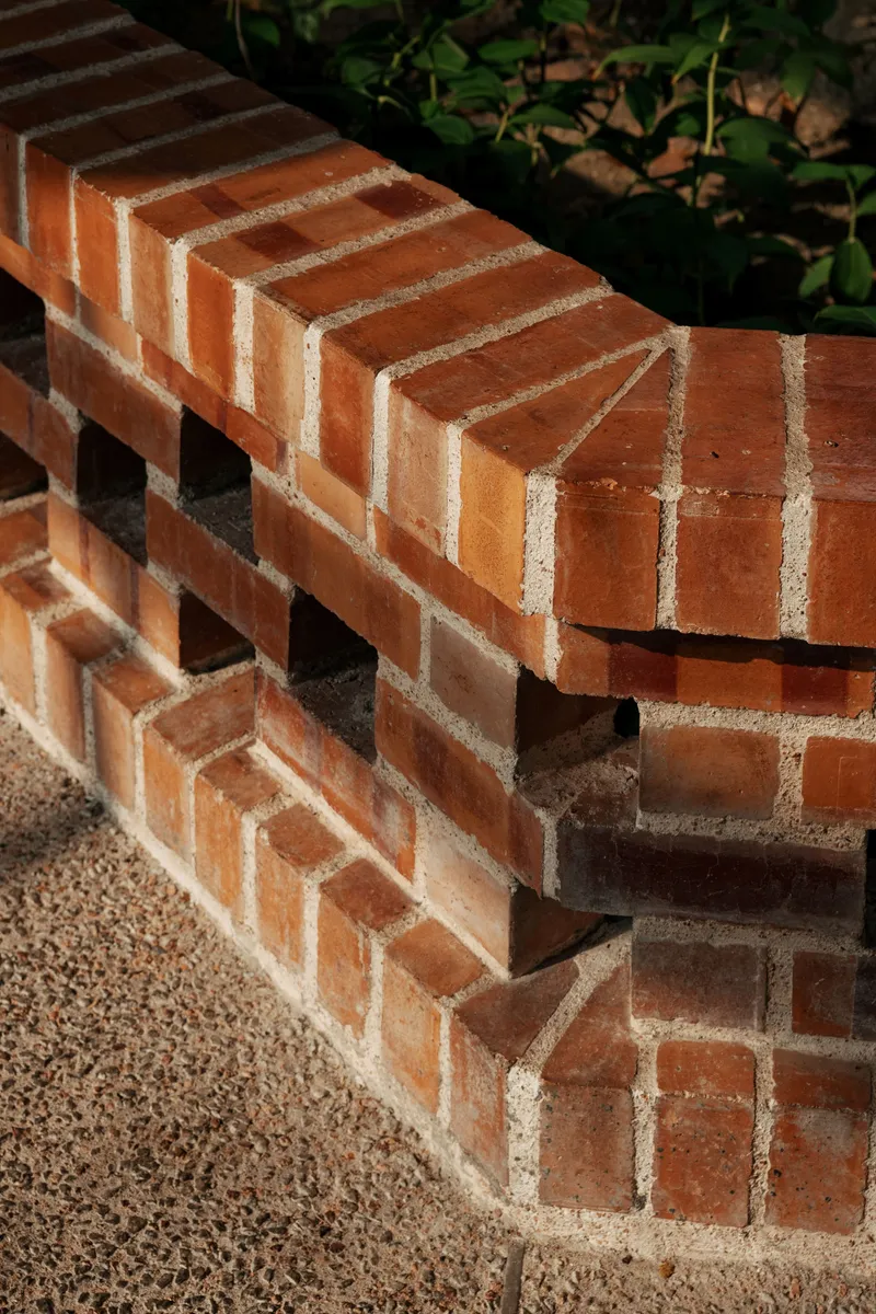 Brick bench detail showing corbelled courses and perforated pattern with gravel base