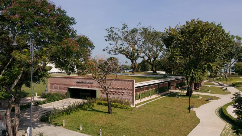Elevated view of the brick-clad pavilion with a planted roof nestled among mature trees in a park setting