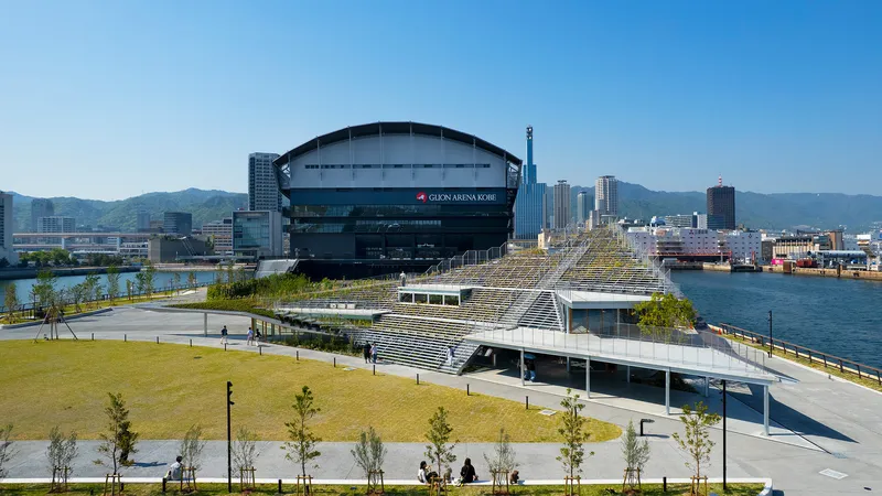 Terraced seating structure with planted steps descending toward the waterfront under clear blue sky