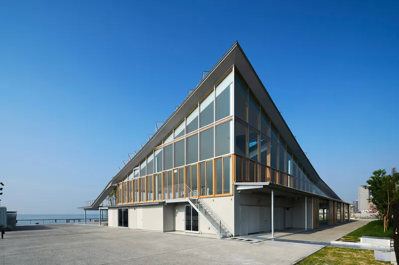 Triangular facade with timber louvres between glazed upper and solid lower levels facing waterfront