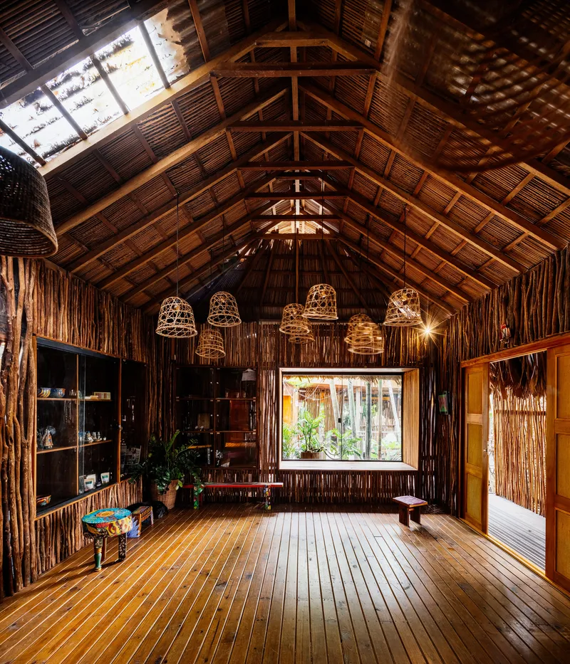 Interior hall with exposed timber trusses, woven rattan pendant lights and glazed opening to garden