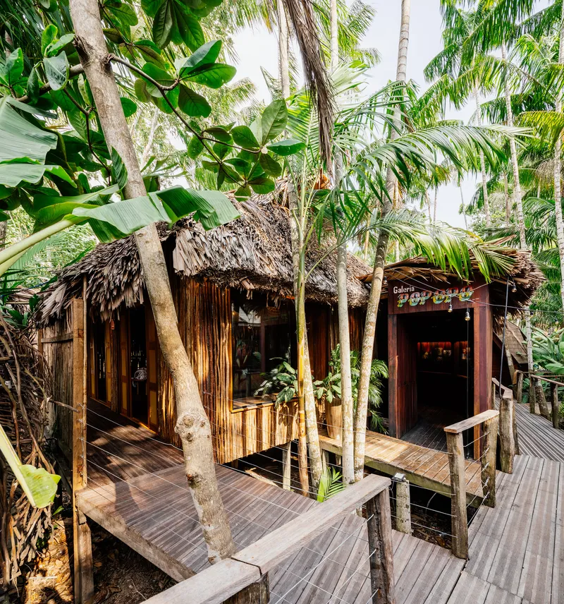 Elevated wooden deck surrounding palm grove with thatched pavilion nestled among banana plants and palms