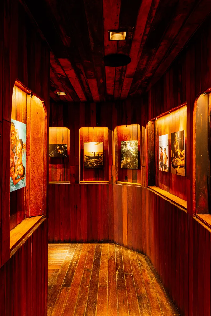 Corner view of exhibition hallway with illuminated photo frames set into timber paneled walls