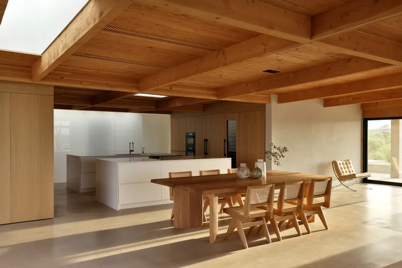 Open-plan kitchen and dining area with exposed timber beams and clerestory skylights