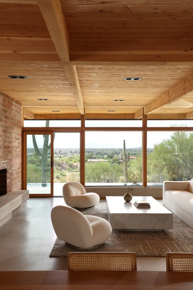 Living space with horizontal timber window frames overlooking saguaro cactus in the desert beyond