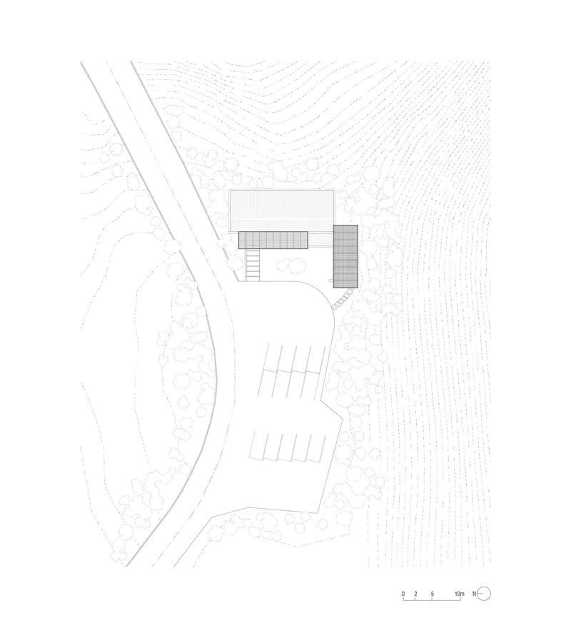 Site plan drawing showing two building volumes beside a curved driveway and topographic contour lines