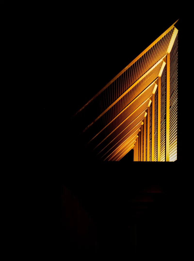 Triangular timber roof corner illuminated at night showing layered panel construction