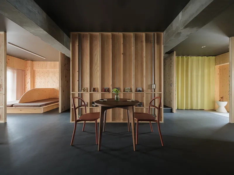 Round dining table with three chairs centered beneath vertical timber slat wall divider