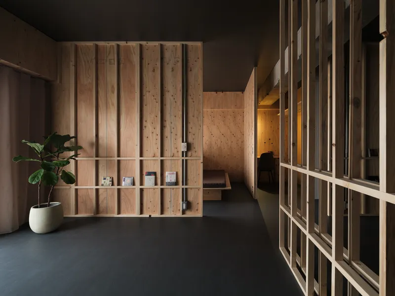 Reception area with vertical timber slat partitions and floating display shelves beside a potted plant